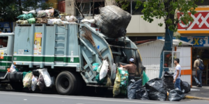 A person loading garbage on the garbage truck