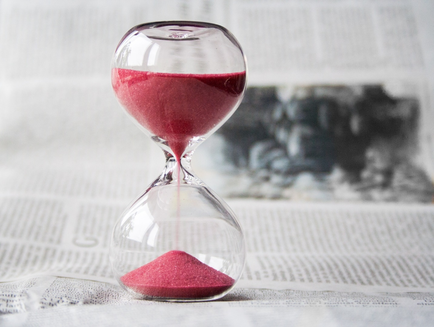 Hourglass with Red Sand on Newspaper
